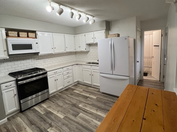 Remodeled kitchen with white cabinetry and wood floors