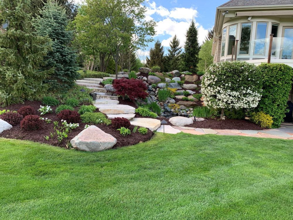 Stone staircase surrounded by various bushes, rocks, and flowers