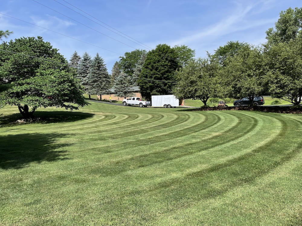 A Sustain Services truck parked in the driveway of a freshly mowed property