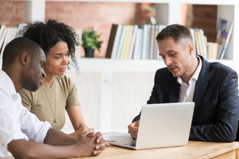 Realtor explaining information to a couple on a laptop